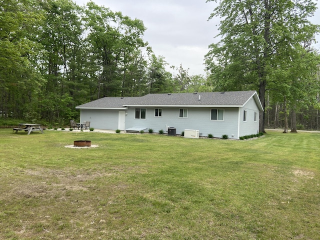 3350 Woodcrest Dr, Lewiston, MI 49756 - back of property with a lawn, a fire pit, and roof with shingles