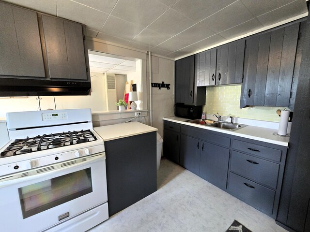 7931 Mill St, Vanderbilt, MI 49795 - kitchen with white gas range oven, light countertops, backsplash, under cabinet range hood, and a paneled ceiling