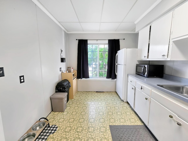 7931 Mill St, Vanderbilt, MI 49795 - kitchen with light countertops, freestanding refrigerator, white cabinets, a drop ceiling, and light flooring