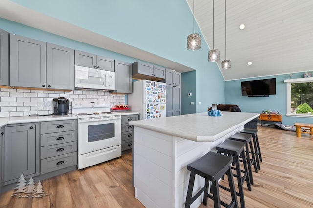 4620 Pinewood Dr, Lewiston, MI 49756 - kitchen with white appliances, gray cabinetry, a breakfast bar area, light countertops, and light wood-style floors