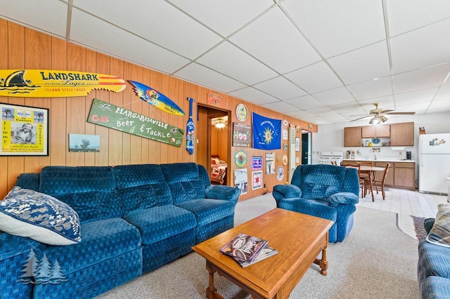 2911 Birch St, Lewiston, MI 49756 - living room featuring light carpet, a ceiling fan, a drop ceiling, and wooden walls
