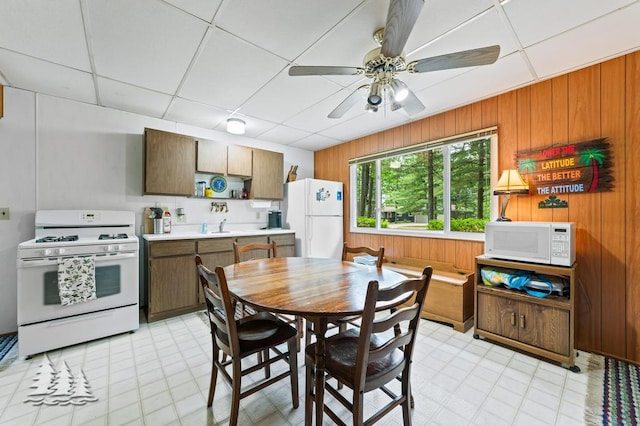 2911 Birch St, Lewiston, MI 49756 - dining area with ceiling fan, a drop ceiling, wooden walls, and light flooring