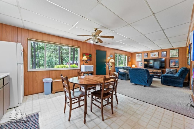2911 Birch St, Lewiston, MI 49756 - dining area featuring light floors, wooden walls, a drop ceiling, and a ceiling fan