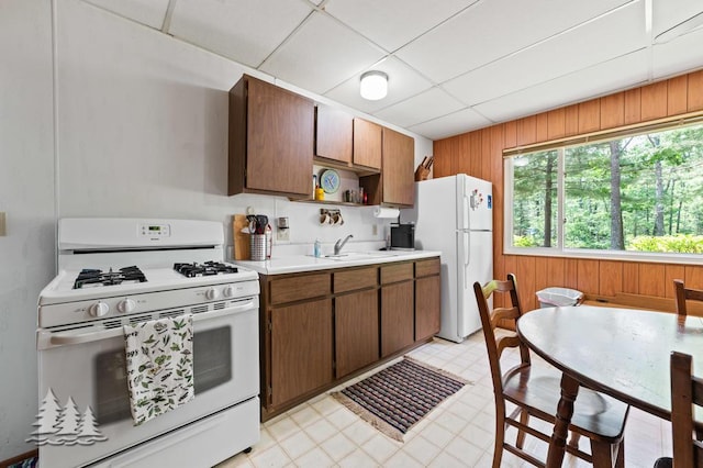 2911 Birch St, Lewiston, MI 49756 - kitchen featuring white appliances, wood walls, light countertops, a paneled ceiling, and light flooring