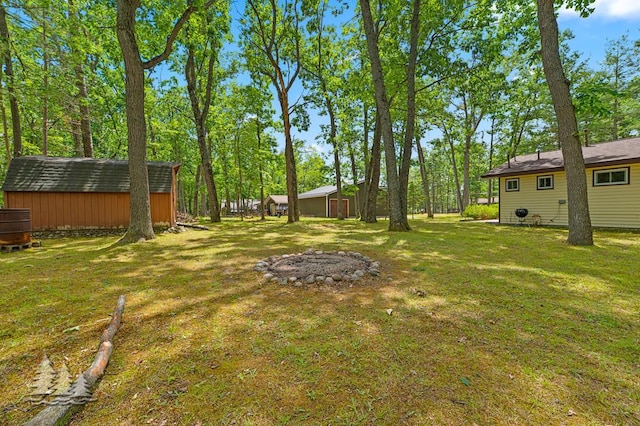 2911 Birch St, Lewiston, MI 49756 - view of grassy yard with a storage unit and a fire pit