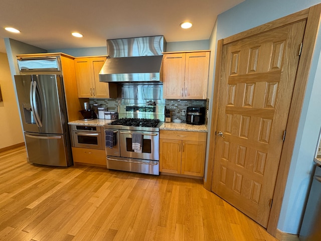 169 Pine Bluffs Rd, Roscommon, MI 48653 - kitchen featuring appliances with stainless steel finishes, wall chimney range hood, light wood finished floors, decorative backsplash, and recessed lighting