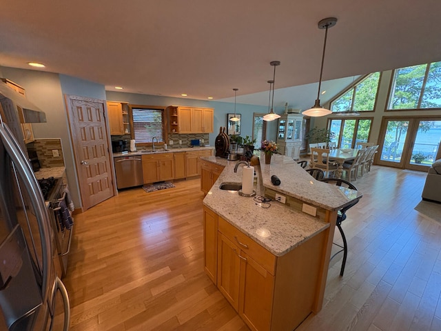 169 Pine Bluffs Rd, Roscommon, MI 48653 - kitchen with stainless steel appliances, a breakfast bar area, light wood finished floors, open shelves, and backsplash