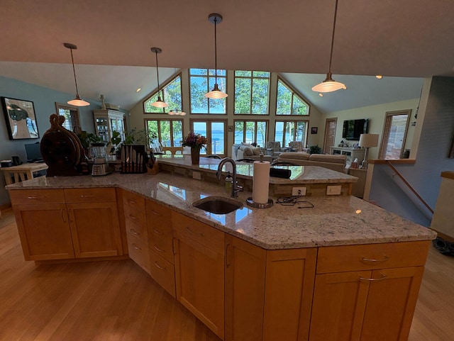 169 Pine Bluffs Rd, Roscommon, MI 48653 - kitchen featuring light wood-style floors, vaulted ceiling, light stone countertops, open floor plan, and decorative light fixtures