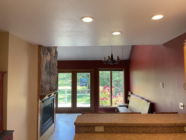 12395 Atkinson Rd, Lachine, MI 49753 - stairs featuring a stone fireplace, a chandelier, a textured ceiling, and recessed lighting