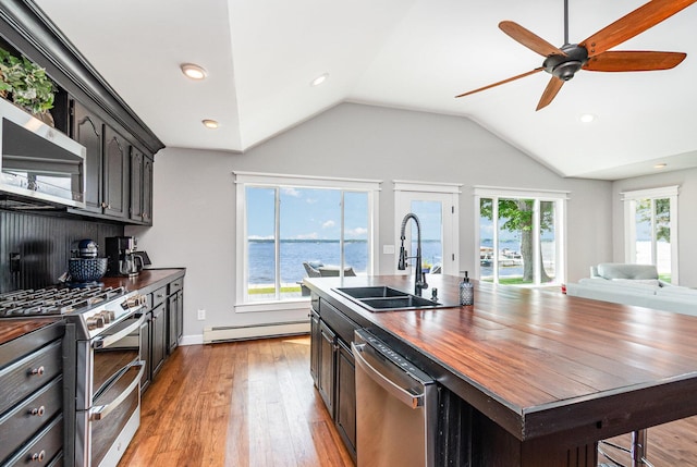 319 Old Trl, Houghton Lake, MI 48629 - kitchen with appliances with stainless steel finishes, light wood-style flooring, a baseboard heating unit, butcher block countertops, and vaulted ceiling