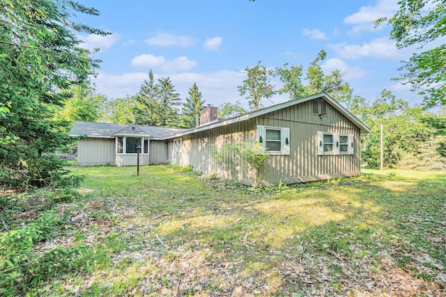 5699 N Red Oak Rd, Lewiston, MI 49756 - view of home's exterior with a chimney and a yard