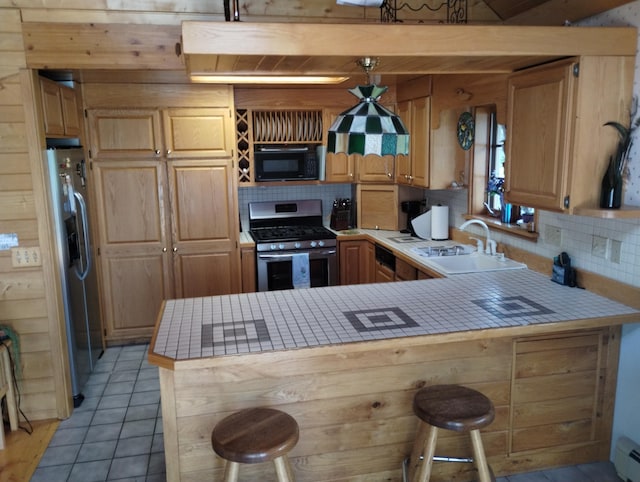 19241 Pine Tree Ct, Hillman, MI 49746 - kitchen featuring stainless steel appliances, tile counters, backsplash, a peninsula, and a breakfast bar area