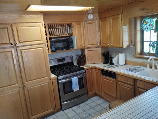 19241 Pine Tree Ct, Hillman, MI 49746 - kitchen with stainless steel range with gas cooktop, tile countertops, black microwave, light tile patterned floors, and backsplash