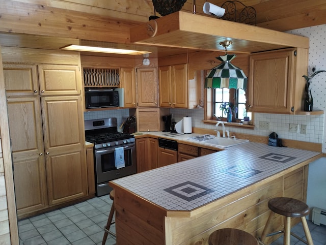 19241 Pine Tree Ct, Hillman, MI 49746 - kitchen featuring stainless steel gas range, tile counters, black microwave, and backsplash