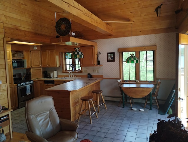 19241 Pine Tree Ct, Hillman, MI 49746 - kitchen with stainless steel gas range, wallpapered walls, black microwave, a peninsula, and wainscoting