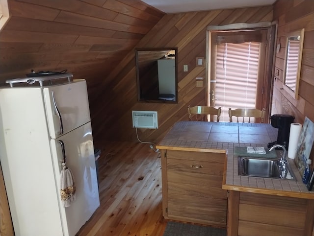19241 Pine Tree Ct, Hillman, MI 49746 - kitchen featuring tile counters, freestanding refrigerator, wood walls, wood-type flooring, and an AC wall unit