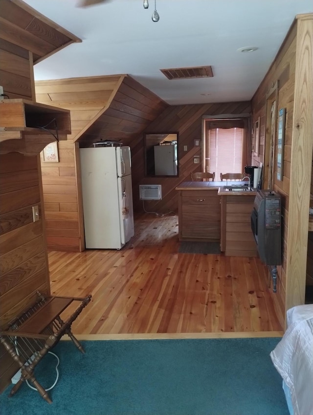 19241 Pine Tree Ct, Hillman, MI 49746 - kitchen featuring freestanding refrigerator, wood walls, light wood-style flooring, and lofted ceiling