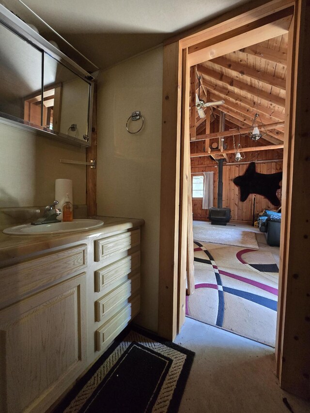 1987 N Galbraith Rd, Mio, MI 48647 - bathroom with vaulted ceiling, wooden walls, a wood stove, and vanity