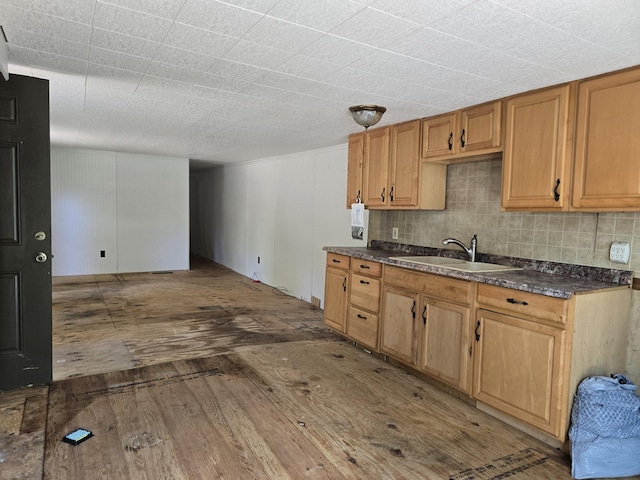 8361 Brookfield Dr, Elmira, MI 49730 - kitchen with wood-type flooring, dark countertops, decorative backsplash, and brown cabinets