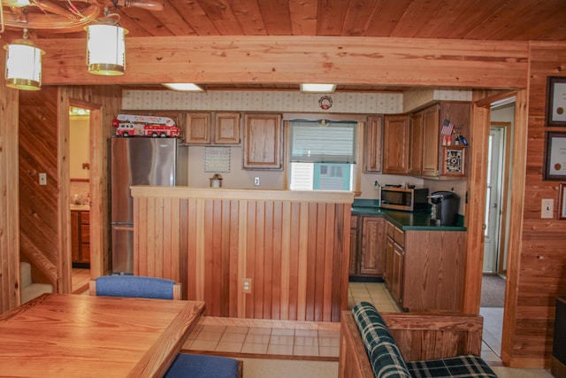 11920 W Shore Dr, Houghton Lake, MI 48629 - kitchen with appliances with stainless steel finishes, wood walls, brown cabinetry, wood ceiling, and light tile patterned flooring