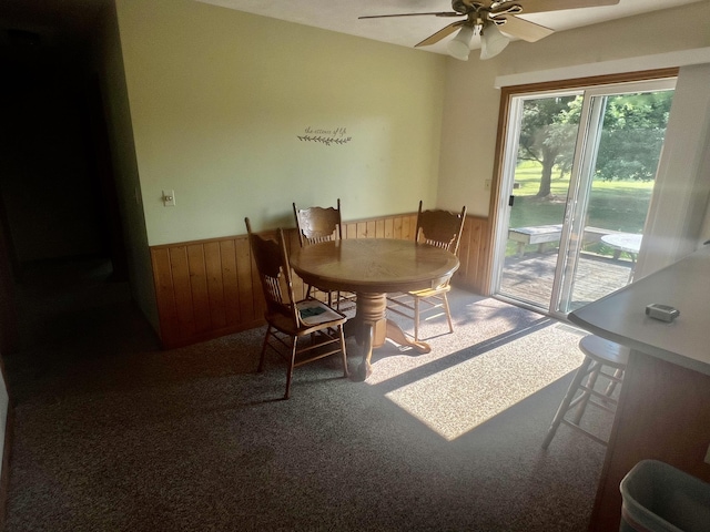 7125 S Military Rd, Grayling, MI 49738 - dining space featuring a wainscoted wall, a ceiling fan, wooden walls, and carpet