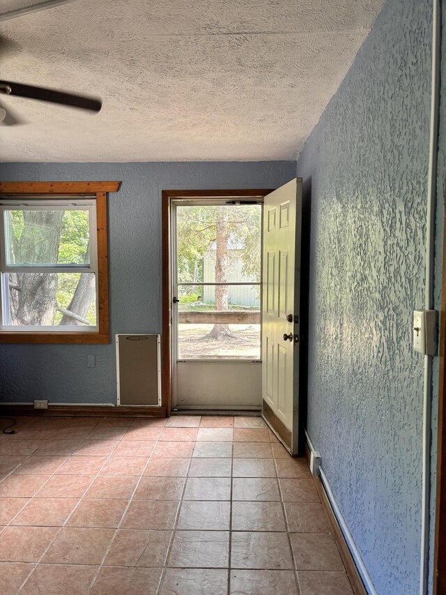 10279 N Sherman Rd, Frederic, MI 49733 - empty room with a textured wall, plenty of natural light, a textured ceiling, ceiling fan, and light tile patterned flooring