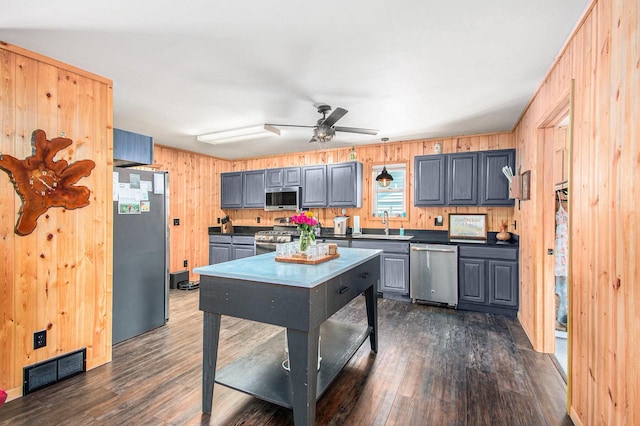 2145 Mustang St, Saint Helen, MI 48656 - kitchen featuring stainless steel appliances, wooden walls, a ceiling fan, dark countertops, and dark wood-style floors