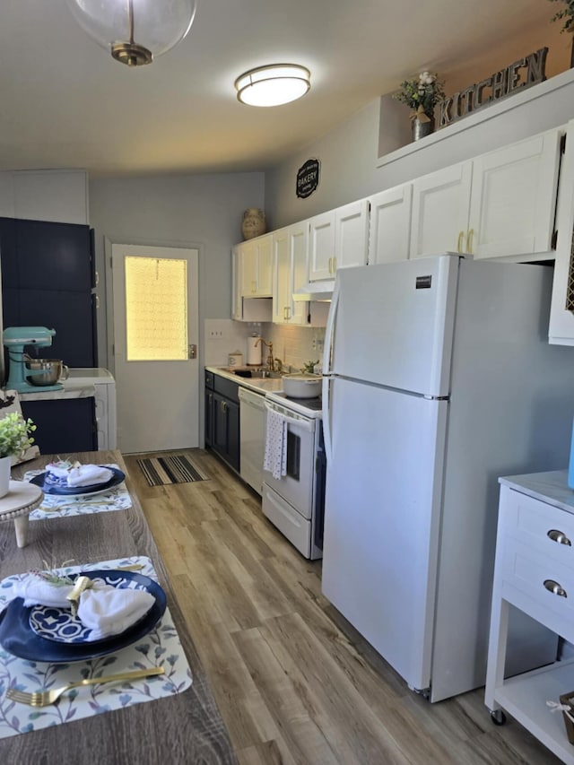 506 S N St, Alpena, MI 49707 - kitchen with white appliances, white cabinets, under cabinet range hood, tasteful backsplash, and light wood-style flooring