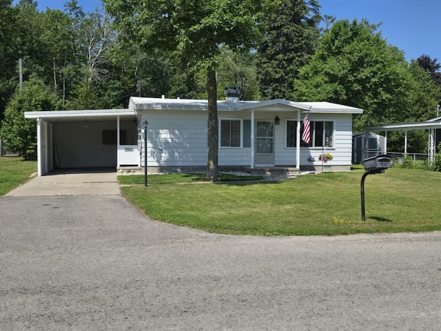 506 S N St, Alpena, MI 49707 - view of front facade with driveway, a front yard, an attached carport, and a chimney