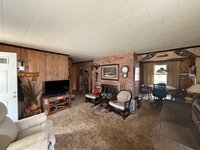 119 Ethel Dr, Roscommon, MI 48653 - living area featuring wooden walls, carpet flooring, and a brick fireplace
