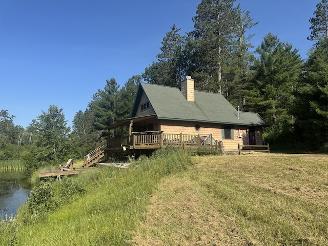 5283 Griffin Rd, Lewiston, MI 49756 - view of side of home with a chimney, a wooden deck, a lawn, and a wooded view