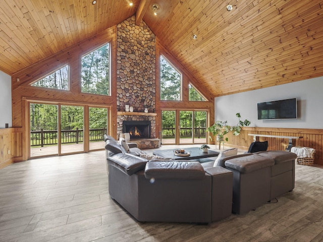 6552 High Trees Ct, Gaylord, MI 49735 - living area featuring high vaulted ceiling, healthy amount of natural light, wood walls, a stone fireplace, and a wood ceiling with exposed beams
