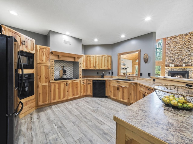 6552 High Trees Ct, Gaylord, MI 49735 - kitchen featuring black appliances, light wood-type flooring, a peninsula, light countertops, and a fireplace