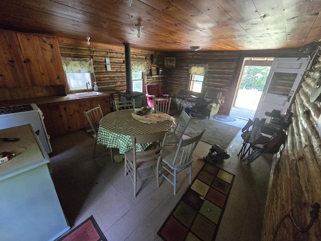 899 Bills Rd, Mio, MI 48647 - dining room featuring rustic walls, a wood stove, wood ceiling, and wood-type flooring