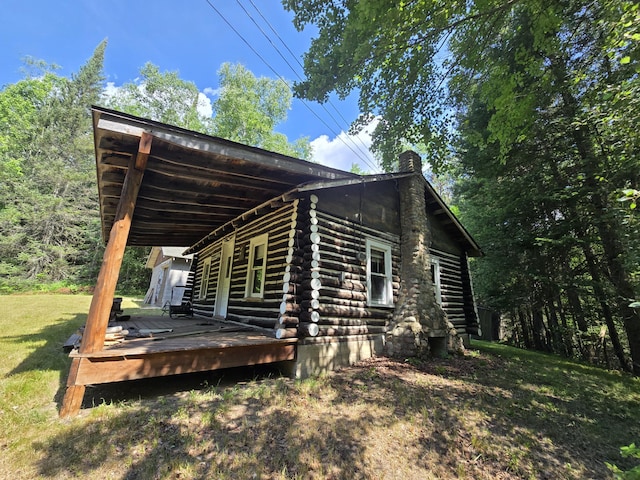 899 Bills Rd, Mio, MI 48647 - view of side of property with log siding, a chimney, a deck, and a yard