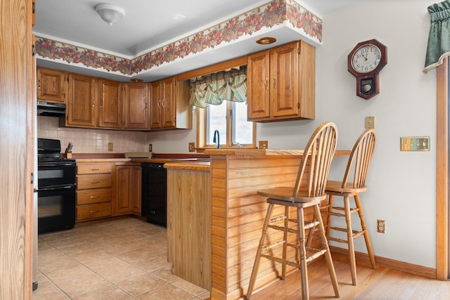 2829 Kassuba Rd, Gaylord, MI 49735 - kitchen with black appliances, exhaust hood, a peninsula, a breakfast bar area, and tasteful backsplash