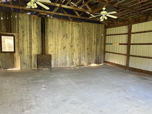 605 N Poor Farm Rd, Harrisville, MI 48740 - garage featuring a wood stove and a ceiling fan