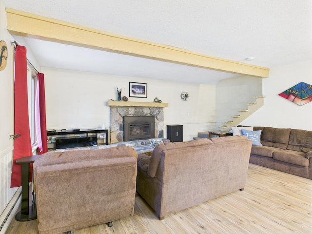 5589 Algonquin Rd, Gaylord, MI 49735 - living area with baseboard heating, stairway, wood finished floors, beam ceiling, and a stone fireplace