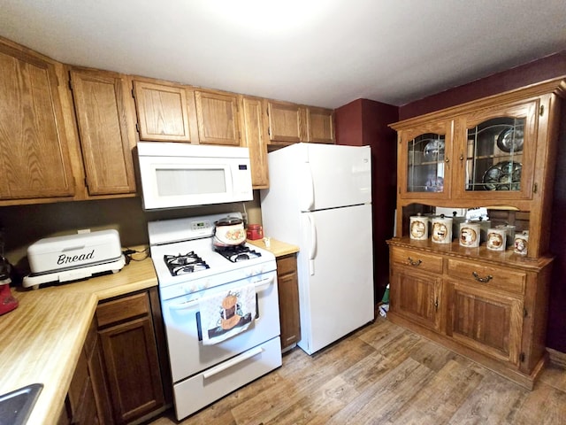 6416 Jimary Ln, Gladwin, MI 48624 - kitchen with white appliances, light countertops, light wood-style floors, glass insert cabinets, and brown cabinets