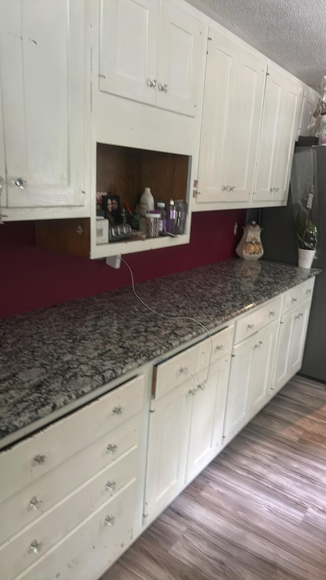 6119 W Nestel Rd, Houghton Lake, MI 48629 - kitchen featuring white cabinets, dark wood finished floors, a textured ceiling, and dark stone countertops
