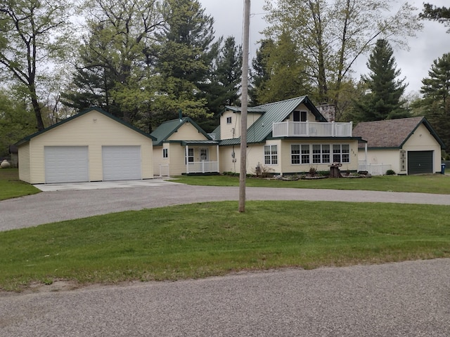 117 Vienna Ct, Houghton Lake, MI 48629 - view of front of property featuring a front lawn, a detached garage, a metal roof, an outdoor structure, and a balcony