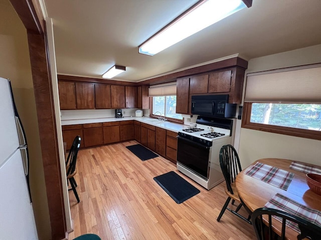 332 Pingree St, Roscommon, MI 48653 - kitchen featuring black microwave, gas stove, light countertops, light wood finished floors, and freestanding refrigerator