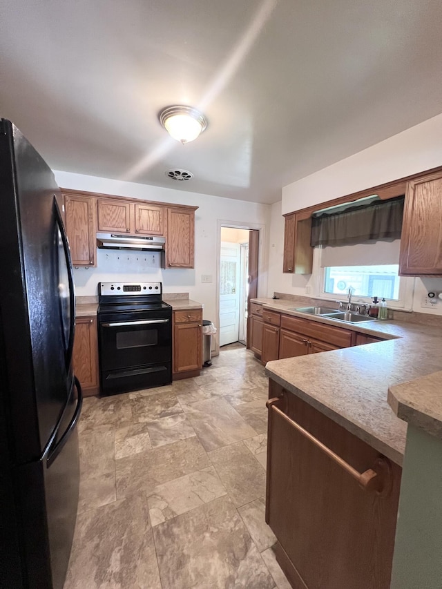 1003 Ada St, Owosso, MI 48867 - kitchen with black appliances, under cabinet range hood, brown cabinetry, stone finish flooring, and light countertops