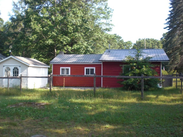557 Davis St, Lake, MI 48632 - view of side of home with a metal roof, a storage unit, and a chimney
