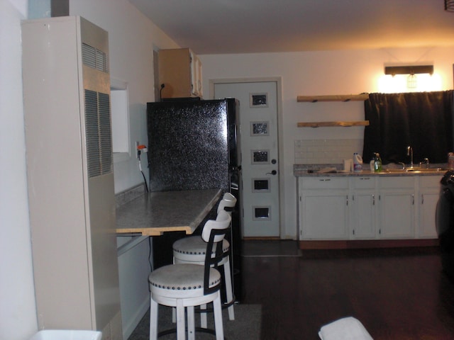 557 Davis St, Lake, MI 48632 - kitchen with a heating unit, open shelves, white cabinetry, dark wood-style flooring, and freestanding refrigerator
