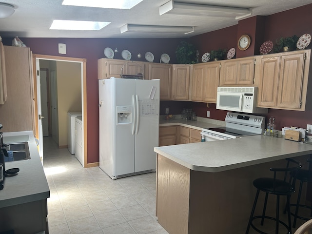 362 N Addison St, Alpena, MI 49707 - kitchen featuring white appliances, light brown cabinetry, a skylight, light countertops, and a peninsula