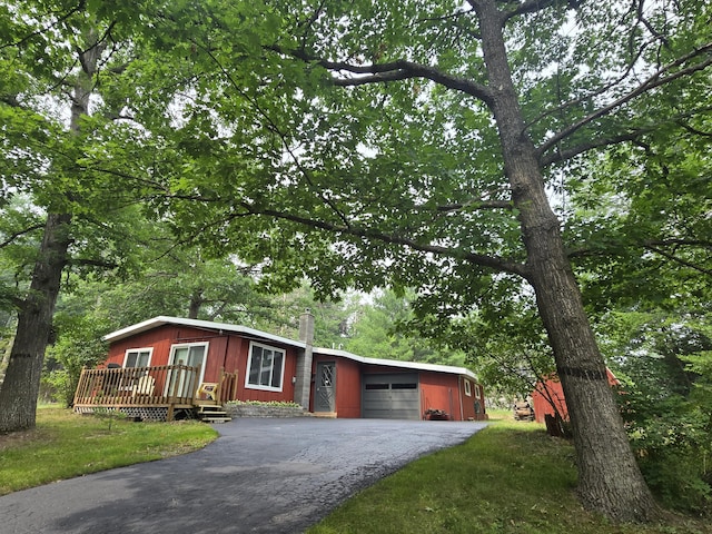 1300 Geesey Ave, Mio, MI 48647 - view of front facade with asphalt driveway, an attached garage, a wooden deck, and a chimney