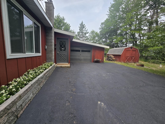 1300 Geesey Ave, Mio, MI 48647 - view of home's exterior with asphalt driveway, a storage unit, a chimney, and board and batten siding