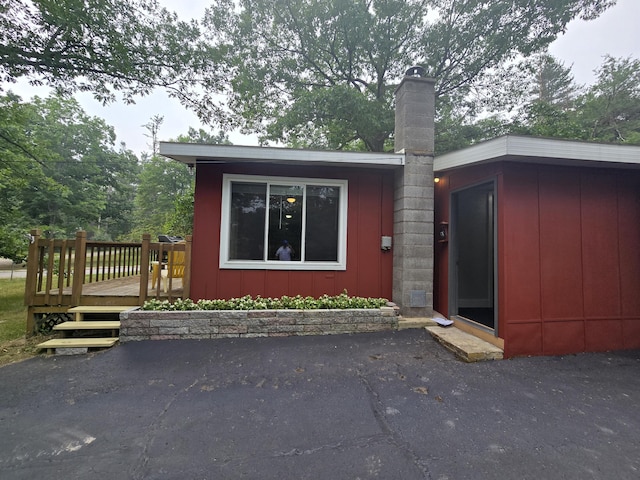 1300 Geesey Ave, Mio, MI 48647 - view of front of house with a chimney, a deck, and board and batten siding