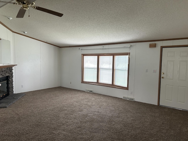 2503 W Hubbard Lake Trl, Hubbard Lake, MI 49747 - unfurnished living room with ornamental molding, a textured ceiling, a glass covered fireplace, carpet flooring, and a ceiling fan